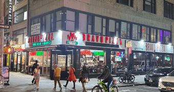 people walking and biking on a city street at night