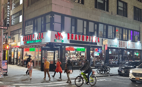 people walking and biking on a city street at night