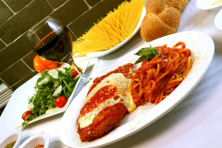 there is a plate of spaghetti and meat with a glass of wine