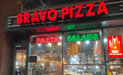 arafed pizza restaurant with a neon sign and a pizza stand