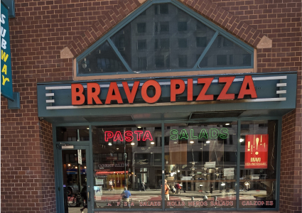 arafed brick building with a pizza shop front and a sign that says bravo pizza