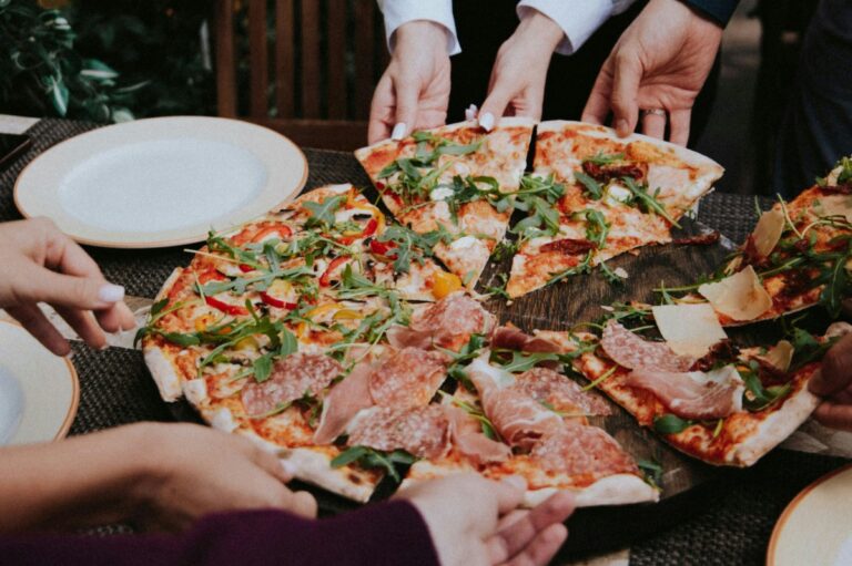 several people are holding slices of pizza on a table