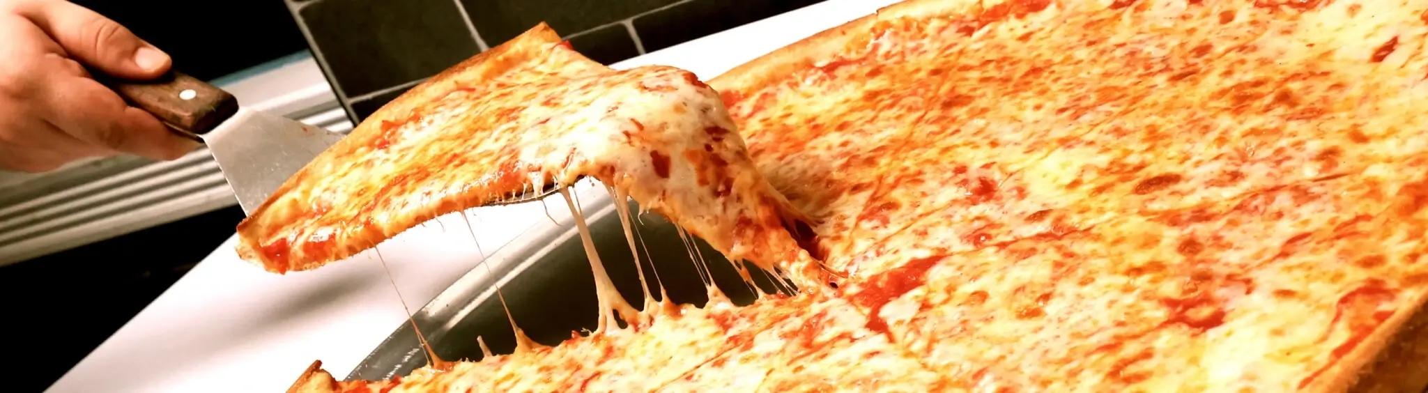 someone is cutting a slice of pizza with a knife